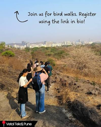 Bird walk group with binoculars on Vetal Tekdi trail overlooking Pune